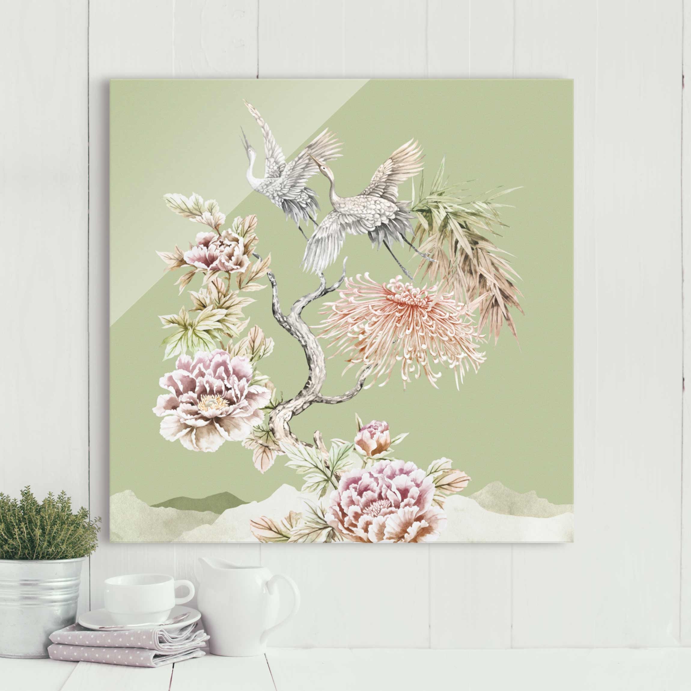 Glasbild Aquarell Störche im Flug mit Blumen auf Grün