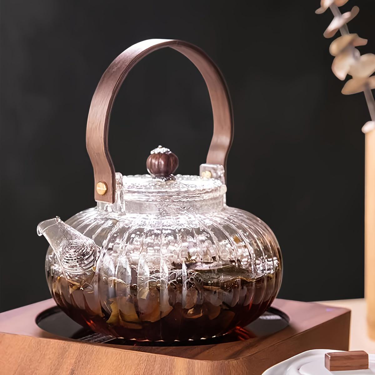 Teekanne aus hitzebeständigem Glas im japanischen Stil mit Holzgriff und Filter für das Aufbrühen auf dem Elektroherd weiß