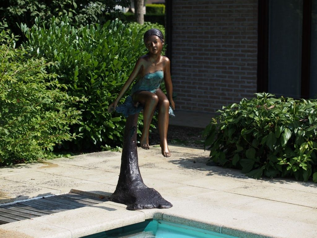 Bronzefigur Mädchen auf Baumstamm